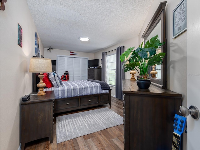 bedroom featuring a closet, a textured ceiling, baseboards, and wood finished floors