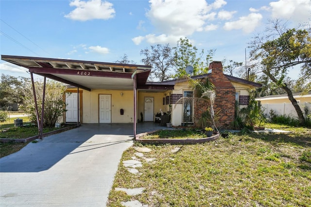 view of front of house featuring a chimney, fence, an attached carport, and concrete driveway