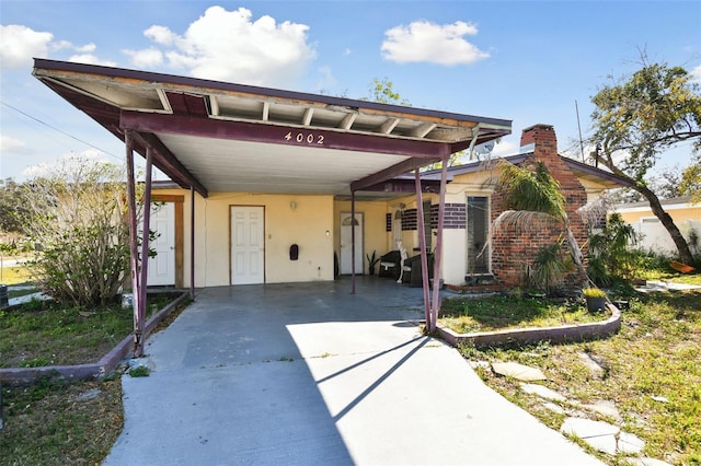 view of front of property with a carport, driveway, and stucco siding