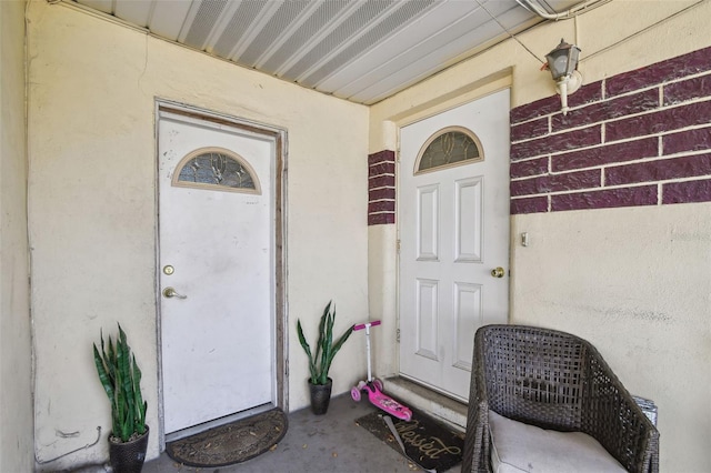 entrance to property featuring brick siding and stucco siding