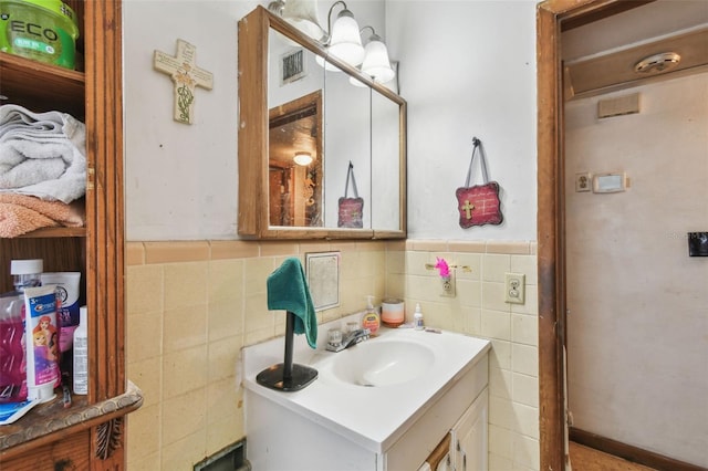 bathroom with wainscoting, visible vents, tile walls, and vanity