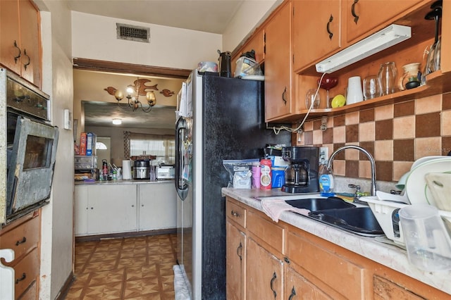 kitchen with visible vents, tile patterned floors, light countertops, a sink, and black oven