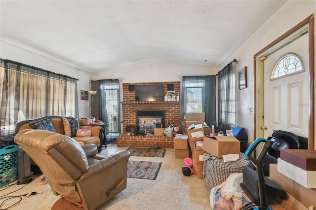 living area with a brick fireplace, vaulted ceiling, and speckled floor