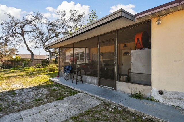 view of side of property featuring a sunroom and fence