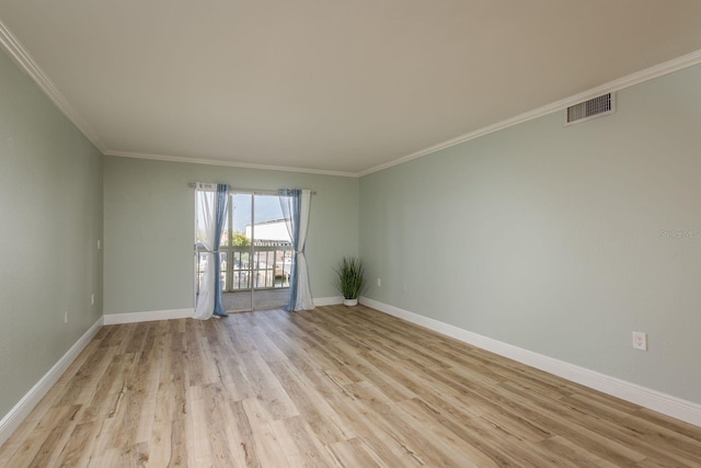 empty room featuring ornamental molding, light wood-style flooring, visible vents, and baseboards