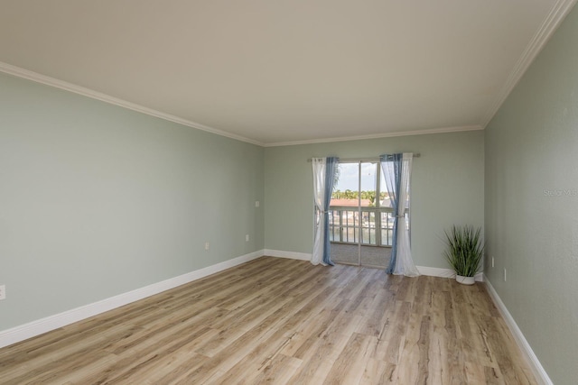 spare room featuring light wood-style floors, crown molding, and baseboards