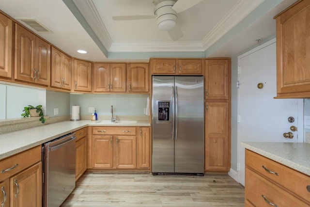 kitchen with a sink, visible vents, appliances with stainless steel finishes, a tray ceiling, and crown molding