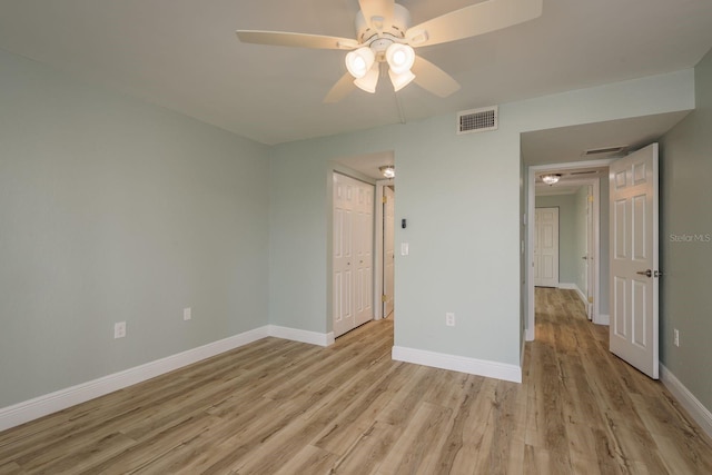 unfurnished bedroom with a closet, visible vents, a ceiling fan, light wood-type flooring, and baseboards