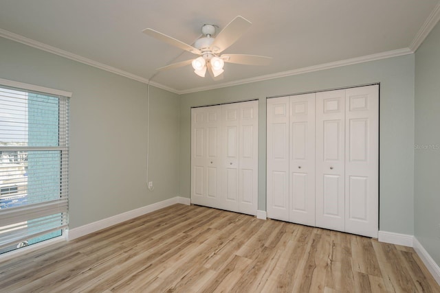 unfurnished bedroom with light wood-style floors, crown molding, baseboards, and two closets