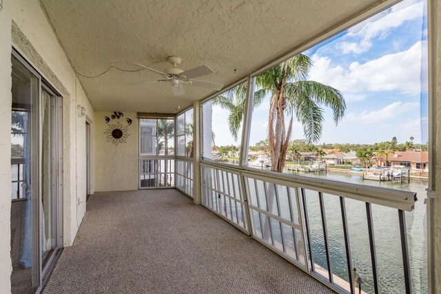 unfurnished sunroom with a water view and ceiling fan