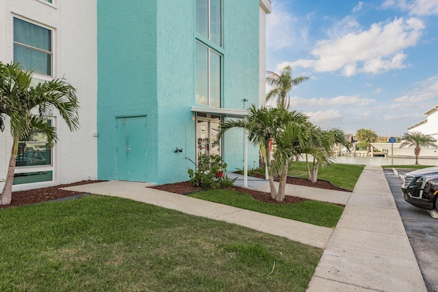 exterior space with stucco siding and a yard