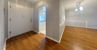 entryway featuring a chandelier, baseboards, and wood finished floors