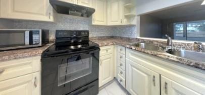 kitchen with black electric range, stainless steel microwave, decorative backsplash, a sink, and extractor fan