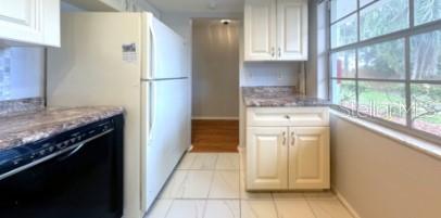 kitchen with dishwasher, light stone counters, and white cabinetry