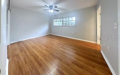 unfurnished room with wood finished floors, a ceiling fan, and baseboards