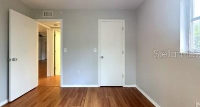 unfurnished bedroom featuring a closet, visible vents, baseboards, and wood finished floors