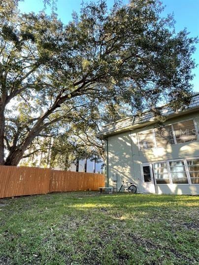 view of side of home featuring fence and a lawn