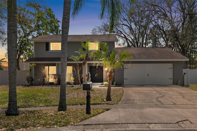 view of front facade featuring driveway, brick siding, an attached garage, and fence