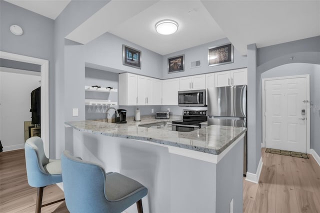 kitchen with visible vents, light stone counters, a peninsula, stainless steel appliances, and open shelves