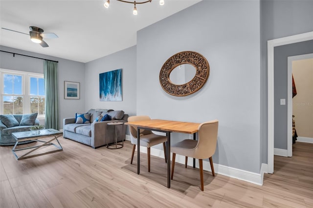 living area featuring baseboards, light wood-style floors, and a ceiling fan