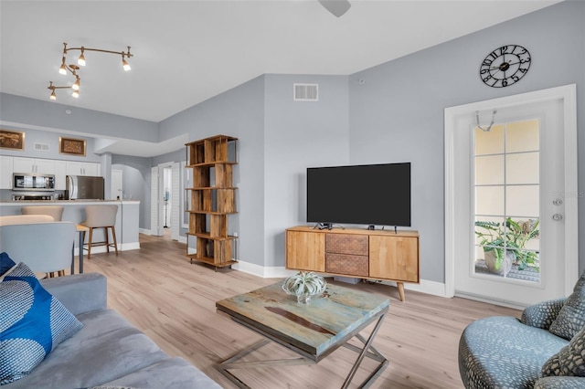 living room with visible vents, arched walkways, baseboards, and light wood finished floors