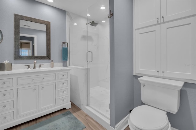 bathroom featuring vanity, toilet, wood finished floors, and a marble finish shower