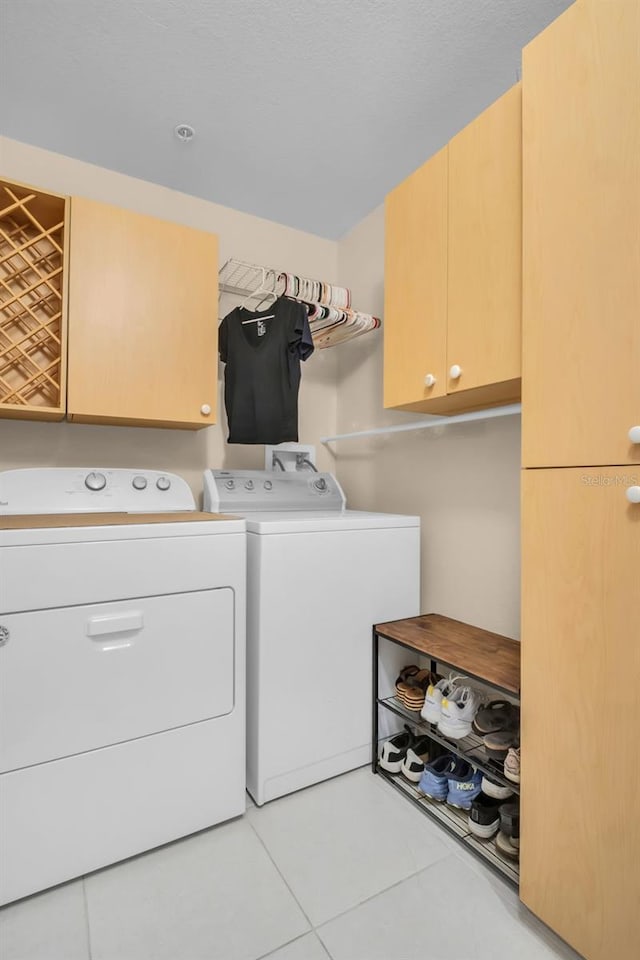 laundry area with tile patterned floors, cabinet space, and washer and clothes dryer