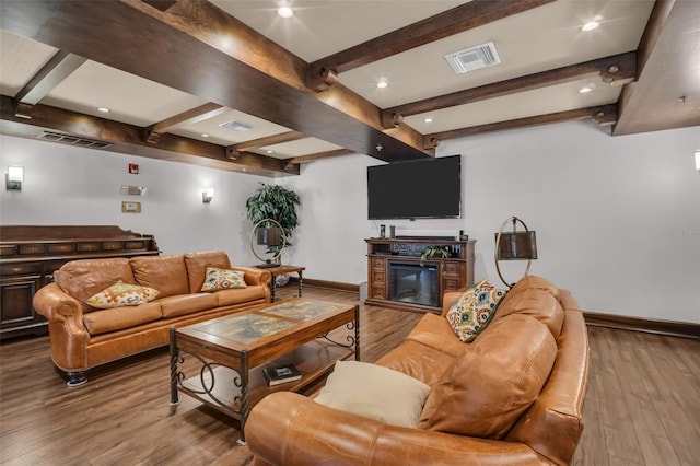 living room featuring a glass covered fireplace, wood finished floors, visible vents, and baseboards