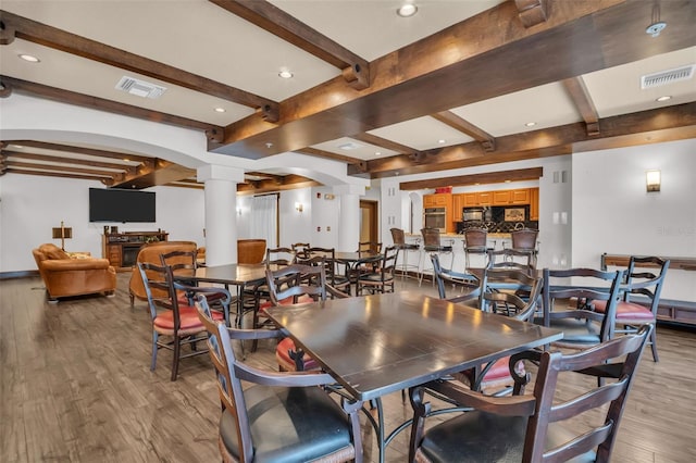 dining area featuring visible vents, beamed ceiling, light wood-type flooring, and decorative columns