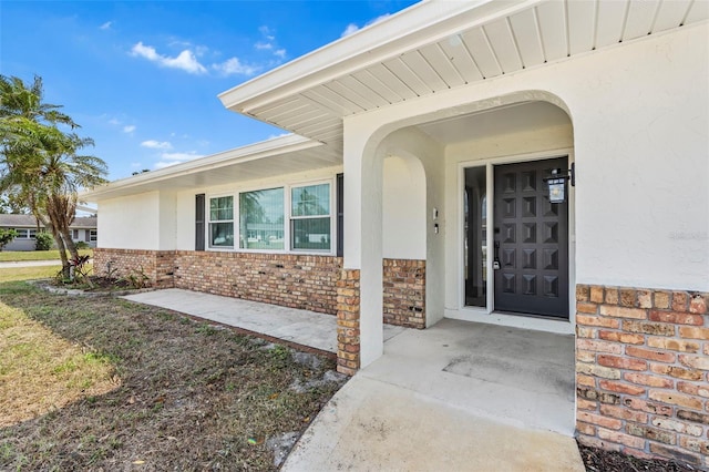 property entrance featuring stone siding, brick siding, and stucco siding