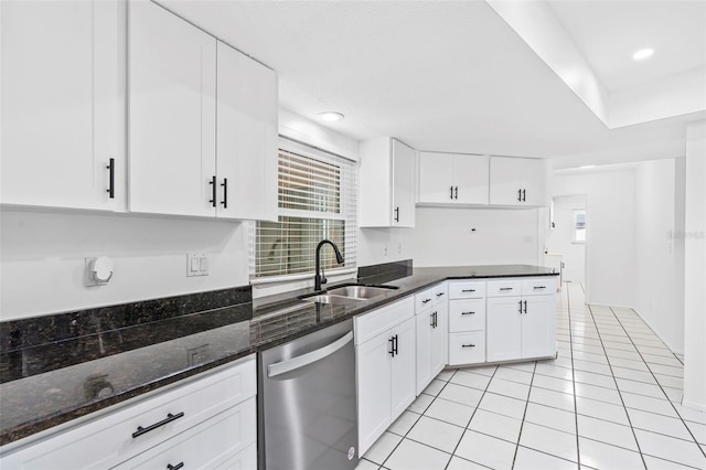 kitchen with light tile patterned floors, white cabinetry, a sink, dark stone countertops, and dishwasher