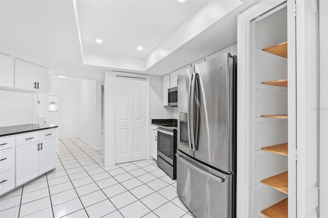 kitchen featuring dark countertops, white cabinetry, stainless steel appliances, and light tile patterned flooring