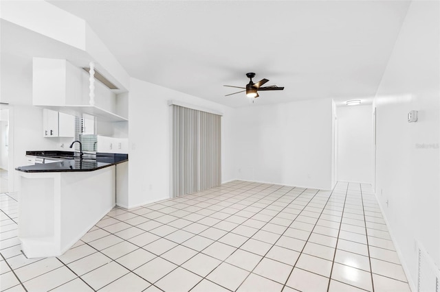 kitchen with open shelves, dark countertops, light tile patterned flooring, ceiling fan, and a peninsula