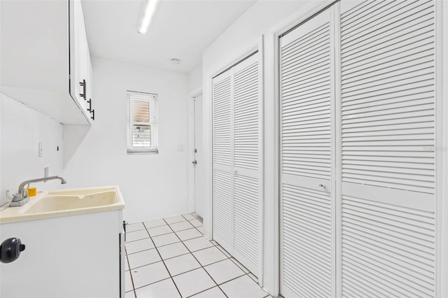 laundry area featuring cabinet space, light tile patterned floors, washer hookup, and a sink