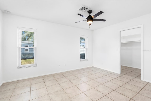 unfurnished bedroom with baseboards, visible vents, a ceiling fan, a walk in closet, and a closet