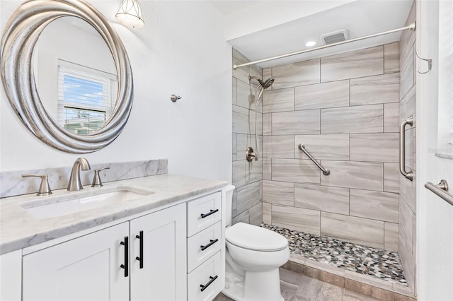 bathroom with toilet, a shower stall, visible vents, and vanity