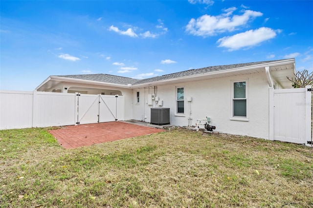 rear view of house featuring a patio, stucco siding, a lawn, central AC unit, and a gate