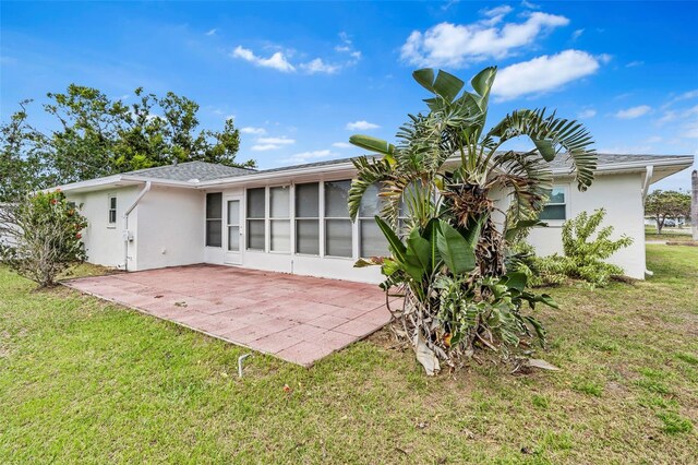 back of property with stucco siding, a lawn, and a patio