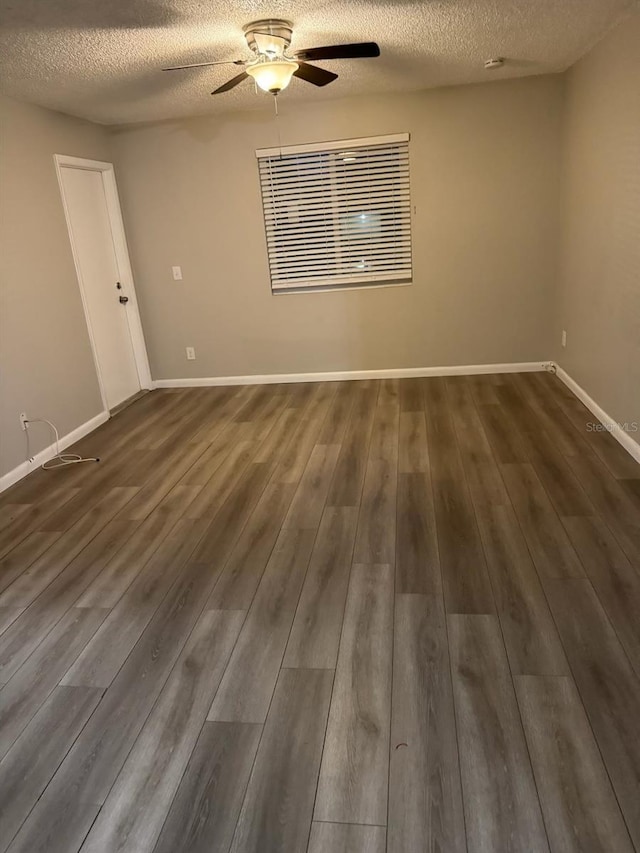 empty room with baseboards, a textured ceiling, ceiling fan, and dark wood-style flooring