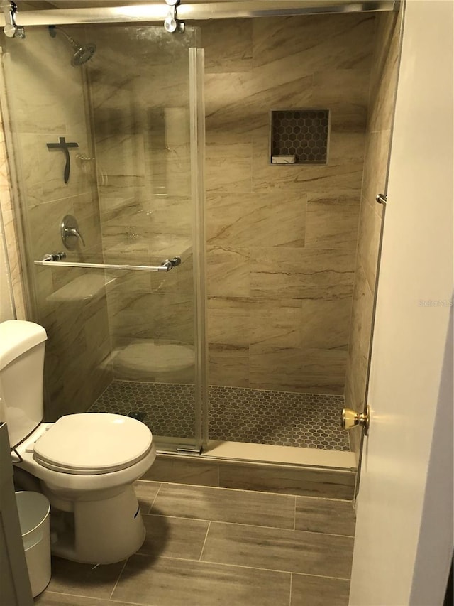 full bathroom featuring a shower stall and toilet