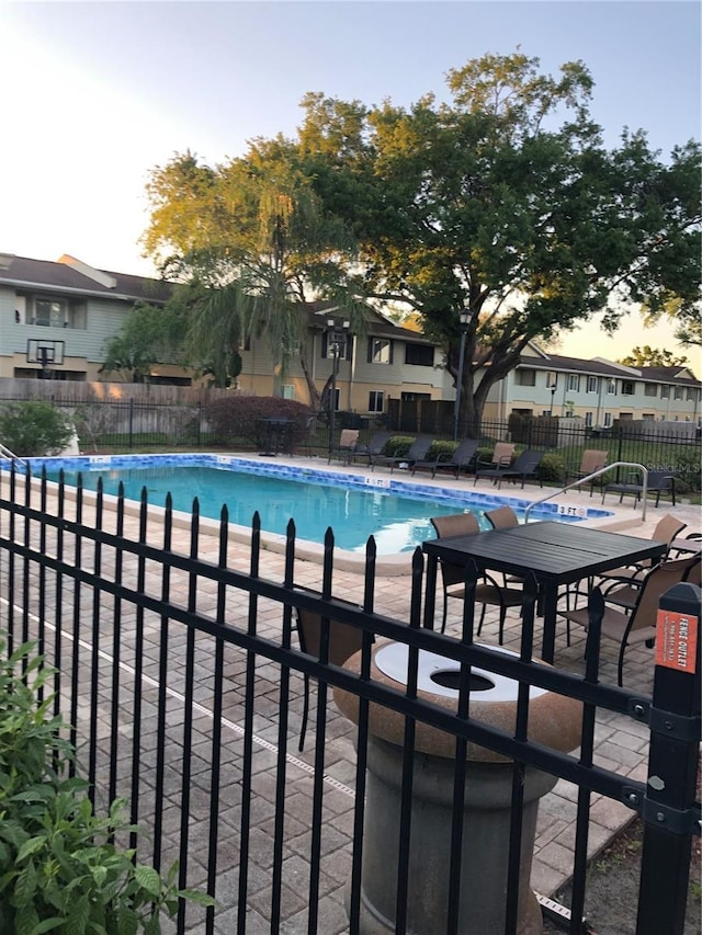 community pool with a patio area and fence