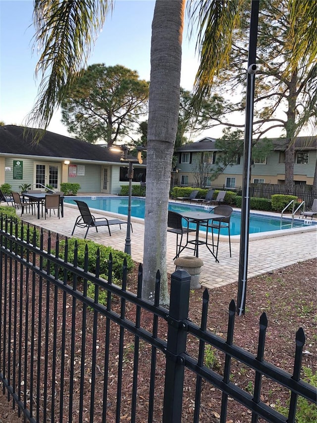 community pool with a patio and fence