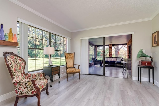 living area featuring light wood-type flooring, baseboards, ornamental molding, and a textured ceiling