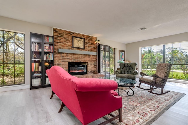 living area with a textured ceiling, a fireplace, visible vents, and wood finished floors