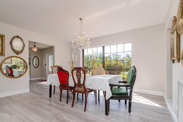dining area featuring light wood-type flooring, an inviting chandelier, and baseboards