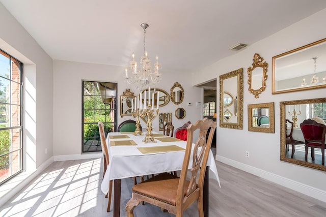 dining room with an inviting chandelier, light wood-style flooring, visible vents, and baseboards