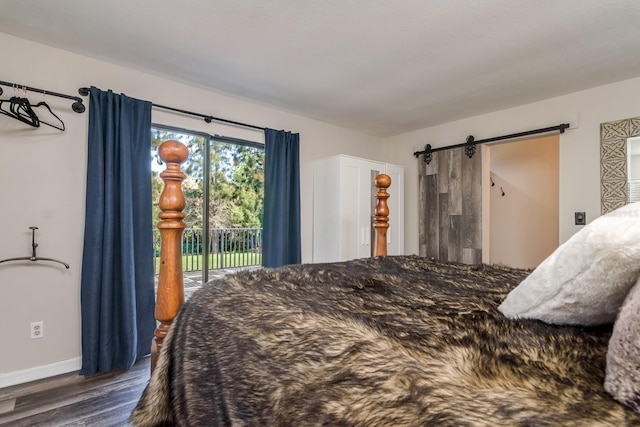 bedroom with access to exterior, a barn door, baseboards, and wood finished floors