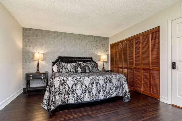 bedroom with a closet, a textured ceiling, baseboards, and wood finished floors