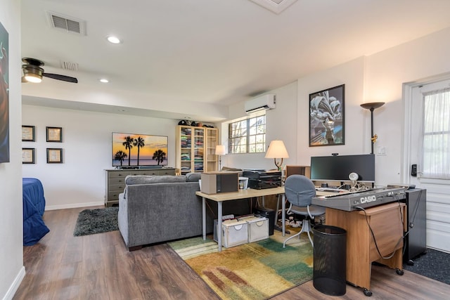 office area with a wall unit AC, wood finished floors, visible vents, and baseboards