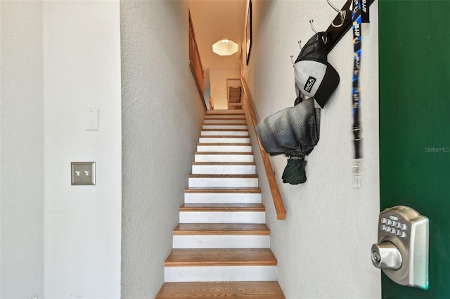 staircase with a textured wall and wood finished floors